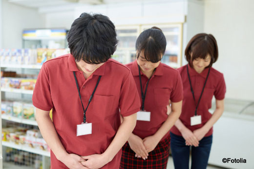 Image shows convenience store workers bowing in Japan.